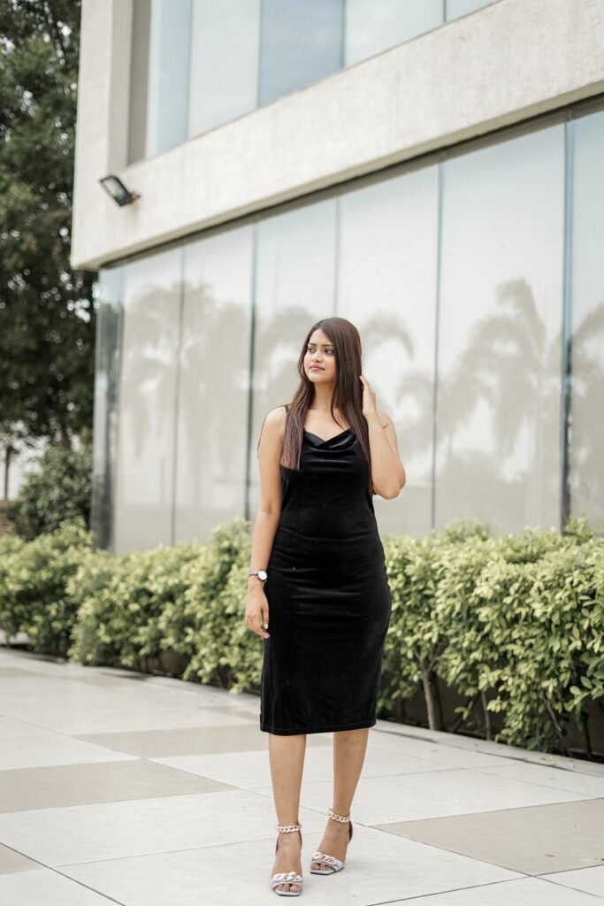 Woman in a black dress posing outside a modern building